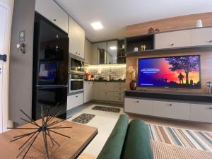 a kitchen with a large screen tv in a living room at Loft Sou Mais Icaraí in Niterói