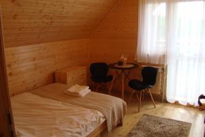 a bedroom with a bed and two chairs and a table at Bieszczadzki Amor in Zawóz