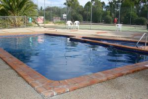 Una piscina de agua con dos sillas blancas. en Capital Country Holiday Park en Canberra