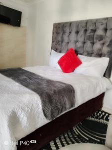 Una cama con una almohada roja encima. en Tenders Accommodation Rooms Mafikeng, en Mahikeng