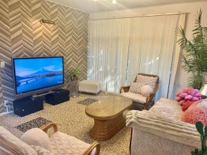 a living room with a tv and a table and chairs at Airportside Chillhouse in Toyonaka