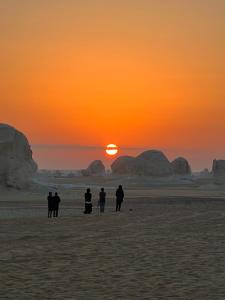 a group of people standing on the beach at sunset at Oasis Camp in Bawati