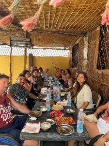 Un gruppo di persone seduti intorno a un tavolo che mangiano cibo di Oasis Camp a Bawati