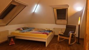 a small bedroom with a bed and a chair at Villa Rennerberg in Radebeul