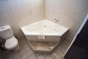 a white bathroom with a tub and a toilet at Mildura Motor Inn in Mildura