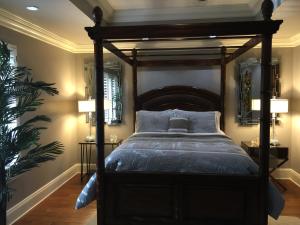 a bedroom with a canopy bed with blue pillows at Louisiana Cajun Mansion in Youngsville