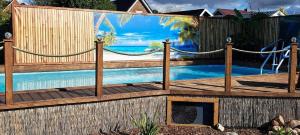 a swimming pool with a wooden fence with a hammock around it at Ferienwohnung Uhlenbusch Paradise in Friesoythe