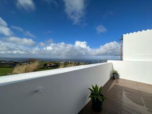 a white wall with two potted plants on a balcony at Achadinha Sunset House in Achadinha