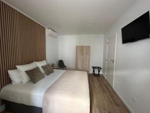 a bedroom with a bed and a flat screen tv at Achadinha Sunset House in Achadinha