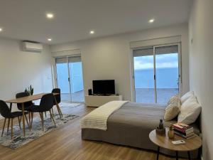 a bedroom with a bed and a table and a television at Achadinha Sunset House in Achadinha