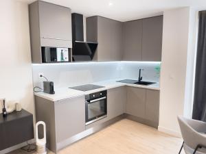 kuchnia z białymi i szarymi szafkami oraz zlewem w obiekcie Appartement Étoilé, Plage, Parking, WiFi, Calme w mieście La Grande-Motte +3 zdjęcia