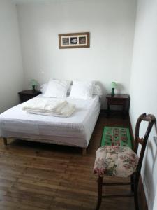 a bedroom with a white bed and a chair at Maison haute 6 pers - plans d'eau centre-ville in LʼAiguillon-sur-Mer