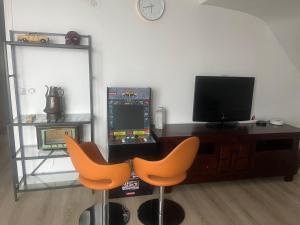 a living room with two orange chairs and a television at Logement entier proche Disneyland in Montry