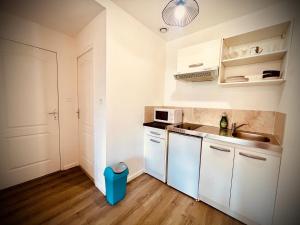 Una pequeña cocina con gabinetes blancos y un fregadero. en Niki, belle vue sur le Loiret, en Saint-Pryvé-Saint-Mesmin