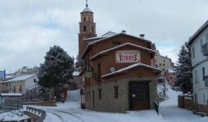 a building with a sign on it in the snow at Hotel Restaurante El CID in Torres de Albarracín