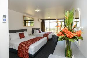 una habitación de hotel con 2 camas y un jarrón de flores en Bluewater Hotel, en Napier
