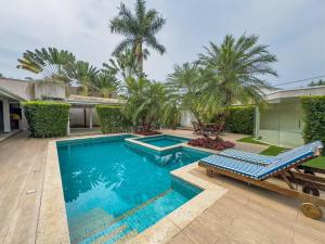 a swimming pool with two blue chairs and palm trees at La Salamandre Paraty in Paraty +64 photos