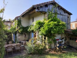 an old house with a table and chairs in front of it at Les Volets Bleus in Arçais