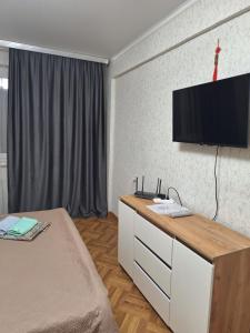 een slaapkamer met een dressoir en een tv aan de muur bij квартира in Balqash