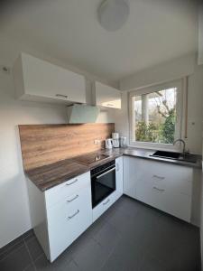 a kitchen with white cabinets and a wooden counter top at Ferienwohnung am Hermannsweg in Tecklenburg