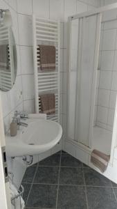 a white bathroom with a sink and a shower at Ferienwohnung Teutoblick in Tecklenburg +10 photos
