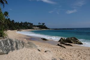 a sandy beach with rocks and the ocean at AQUARIUS Stay in Tangalle