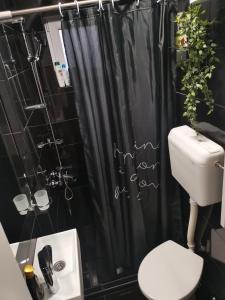 a bathroom with a black shower curtain and a toilet at Stan na dan Pozarevac Apartman Olja in Požarevac
