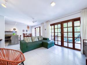 a living room with a green couch and a kitchen at Cond Vista Hermosa - Casas 2 quartos by Pipa Centro in Pipa