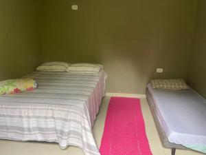 two beds in a room with a pink rug at Chalé do meio in Paraty