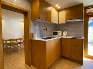 a kitchen with wooden cabinets and a sink and a table at Bonjour Hanok in Gyeongju