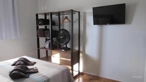 a bedroom with a bed with a fan and a tv at Casa1sn - Casa completa com jardim privativo e chuveirão refrescante! in Serra Negra