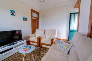 un soggiorno con divano, 2 sedie e TV di Sleep Among the Bananas! Rustic Cottage with Trails at Your Doorstep a Ponta do Sol