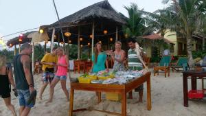 a group of people standing around a table on the beach at Free Beach Resort in Phú Quốc