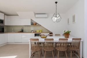 a white kitchen with a table and chairs at Unique 4-Bedroom Villa SemperVivum with pool in Sutivan in Sutivan