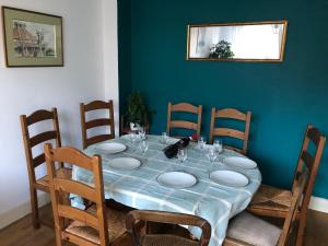 a dining room table with chairs and a blue wall at Chambre Océan, parking gratuit et jardin in Besançon