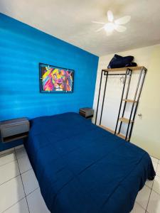a blue bedroom with a bed and a painting on the wall at Departamento a 10 minutos del aeropuerto in El Castillo