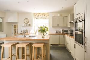 a kitchen with white cabinets and a kitchen island with stools at Bespoke Central Town House in Bath