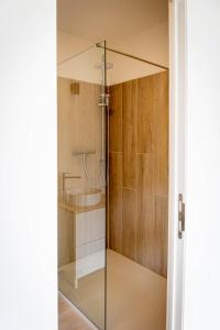 a glass shower with a sink in a bathroom at Le Petit Fief in Couvin