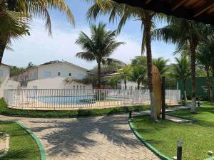 a fence in a yard with palm trees and a house at Casa em Juquehy com muita natureza in São Sebastião