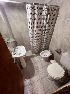 Un baño con inodoro, lavabo y ducha. en La frontera chalet, en Las Toninas