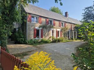 an old house with red windows and a driveway at La forge des vignes in Menetou-Râtel