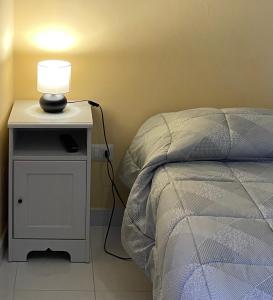 a lamp on a night stand next to a bed at Dimora degli Stradioti in Maschito