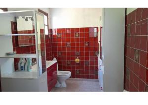 een badkamer met een toilet en rode betegelde muren bij La Bourgandie in Englesqueville-la-Percée