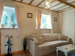 un salon avec un canapé et deux fenêtres dans l'établissement Wesley House Holidays - Choice of 2 Quirky Cottages in 4 private acres, à Redruth