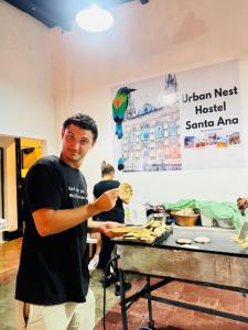 a man standing next to a table with food at Urban Nest Hostel in Santa Ana