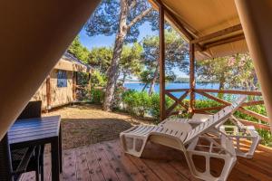 a deck with a lounge chair and a table at Adria Glamping luxury tents Camping Poljana Mali Lošinj in Mali Lošinj