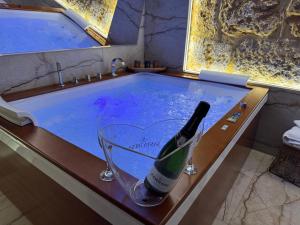 a bottle of wine in a bath tub with a champagne glass at Raquel suite and SPA in Palermo