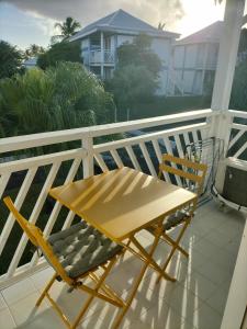 a wooden table and two chairs on a balcony at Studio NIKOTOU - Manganao in Saint-François