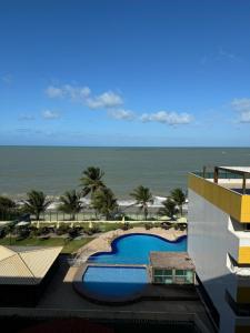 a view of a resort with a swimming pool and the ocean at Cobertura Duplex Pé na Areia 509 Tabatinga Residence in Conde