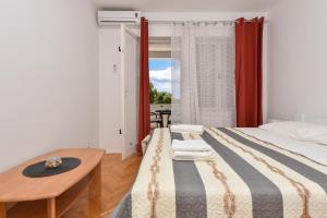 a bedroom with a bed and a table and a window at House Santro in Baška Voda